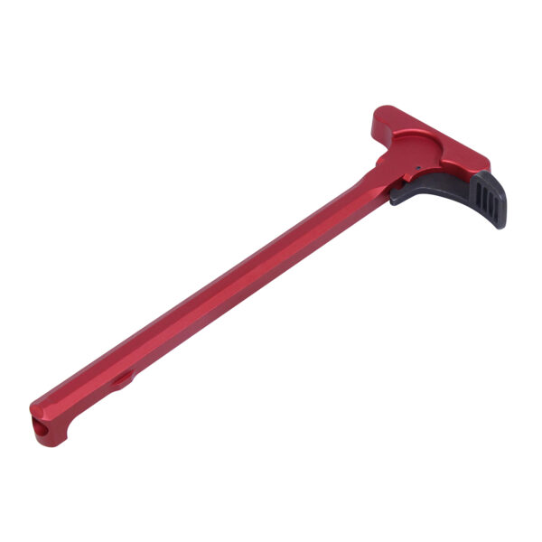 Red anodized AR-15 charging handle against white background.