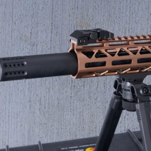 Close-up of modern firearm with suppressor and bronze handguard on bipod.