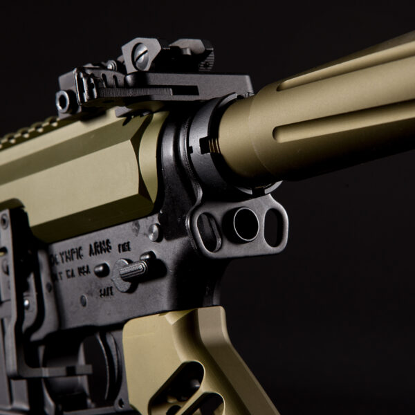 Close-up of tactical firearm with matte gold barrel and black receiver.