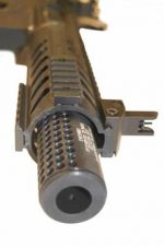 Close-up of tan tactical rifle barrel with flash suppressor and accessory sight rail.