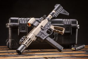 Custom AR-15 pistol with FDE handguard and tactical accessories on wooden surface.