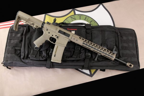 Modern FDE AR-15 rifle with M-LOK handguard and tactical accessories on black gun case.