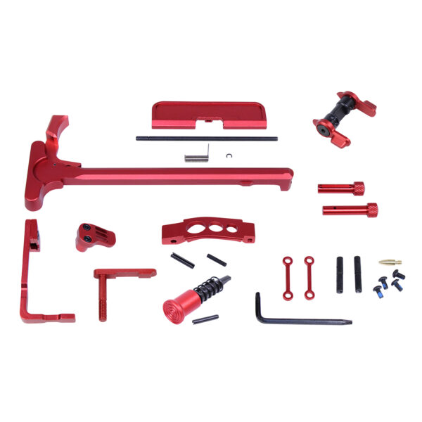 Red anodized firearm assembly kit with charging handle and tools on white background.