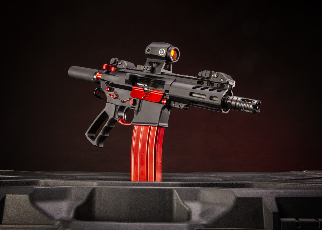 Custom AR-style pistol with red accents and red dot sight on dark background.