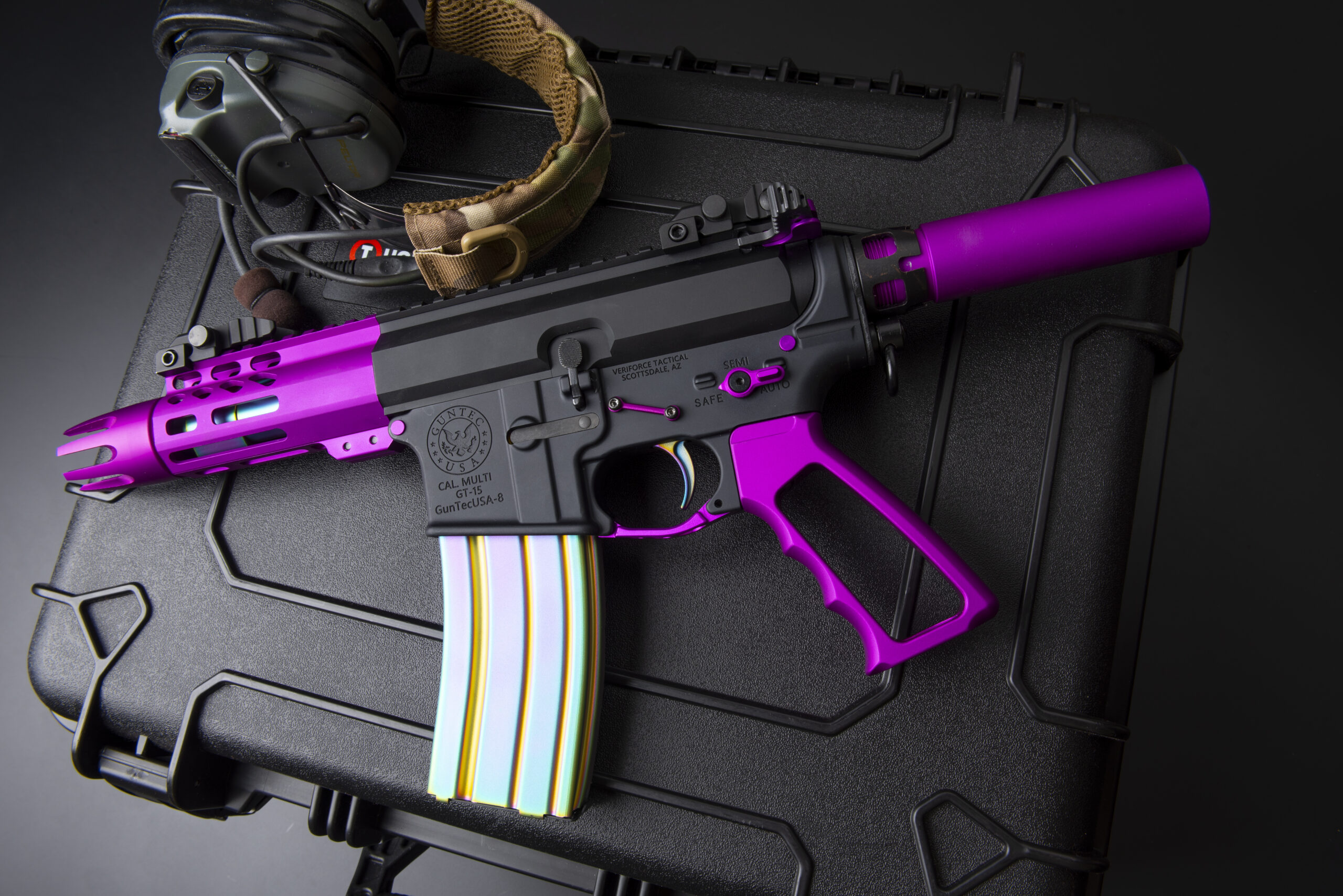 Custom purple and black compact rifle on secure case with tactical headphones.