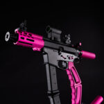 Black and pink tactical pistol with reflex sight and ventilated handguard.