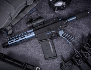 Modern tactical AR-pistol with suppressor and accessories on gray surface.