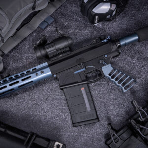 Modern tactical AR-pistol with suppressor and accessories on gray surface.