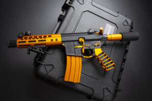 Custom black and orange tactical rifle with suppressor and carrying case.